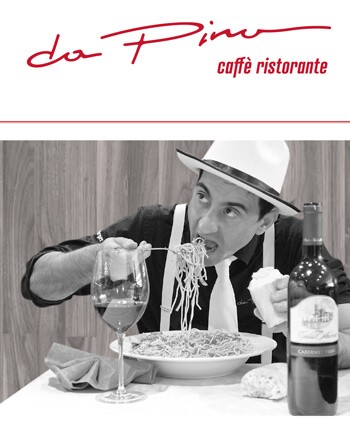 Schwarzweißbild. Mann mit Hut, Hosenträgern und weißer Krawatte isst Spaghetti, Rotweinglas mit Rotweinflasche, Serviette und ein Stück Brot, rotes Logo da Pino caffè ristorante